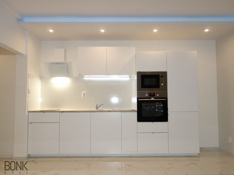 White kitchen unit with an oven and microwave in a 2-room apartment.