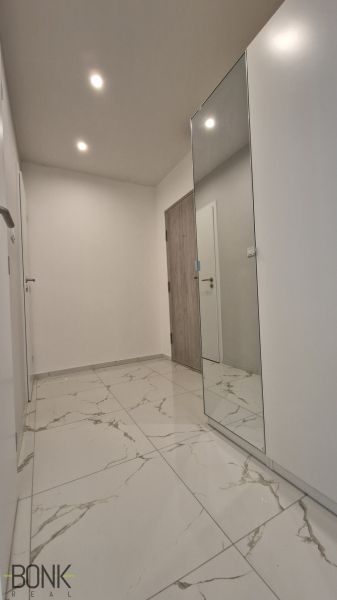 A hallway in a 2-room apartment with a marble floor and a large mirror.