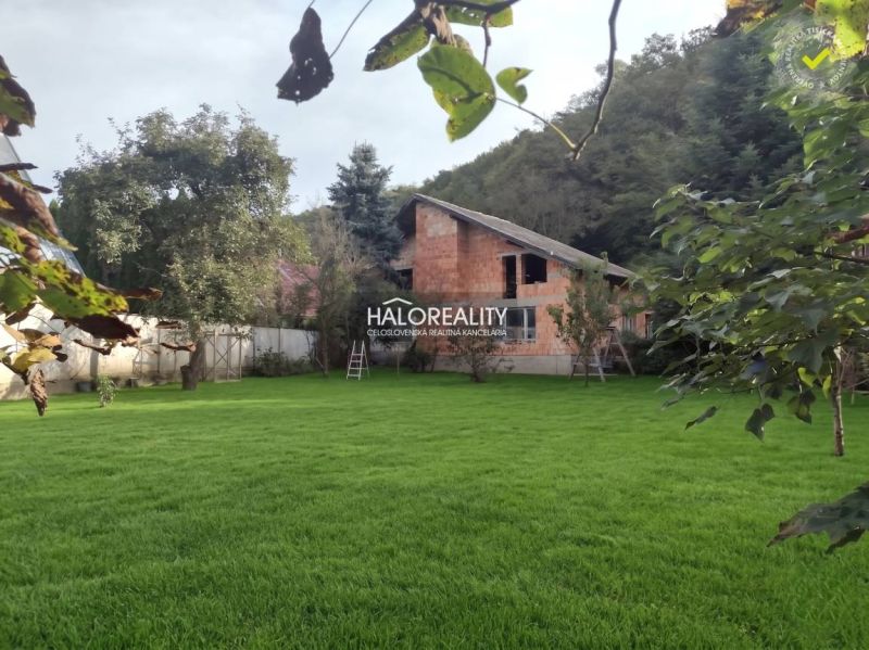 A family house in Poltár surrounded by a lawn and trees in a green environment.