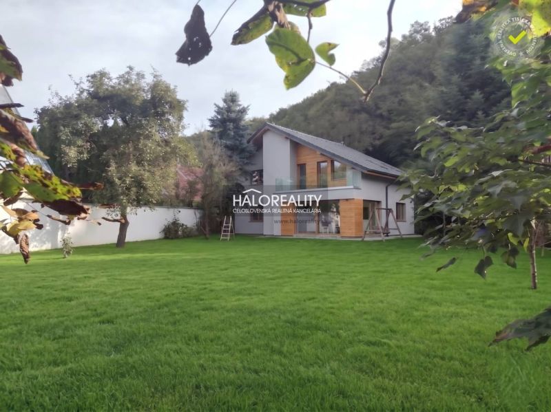 A family house in Poltár surrounded by a lawn and trees, ideal for relaxation.
