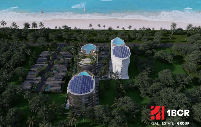 Beachfront apartment development in Phuket with modern buildings and pools surrounded by palm trees.