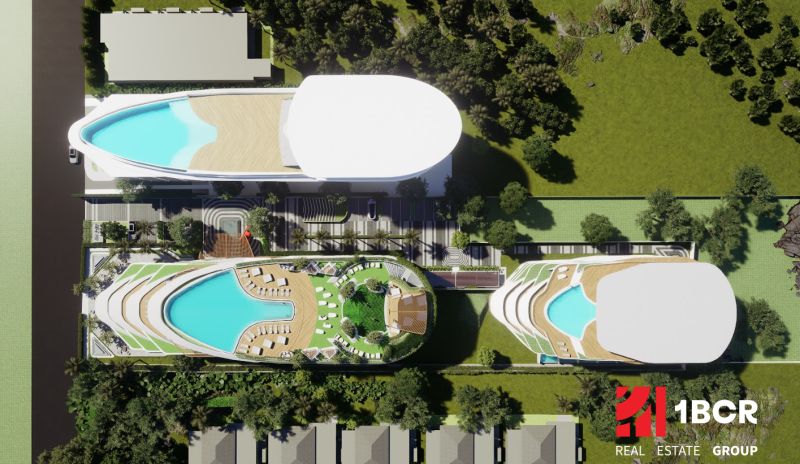 Aerial view of apartment construction in Phuket with rooftop pools and greenery.