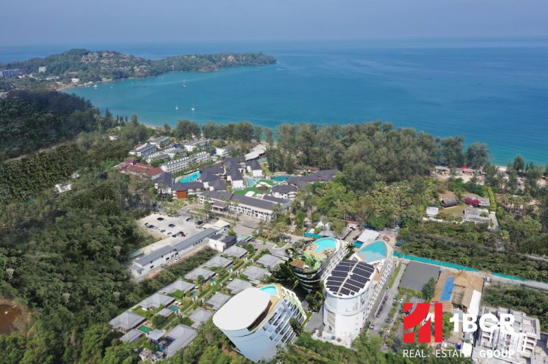 Aerial view of apartment construction near the coast of Phuket with lush greenery.