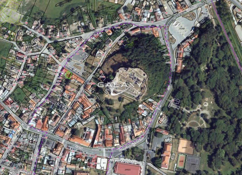 Aerial view of plots in the historical center of Fiľakovo, surrounded by buildings and greenery.