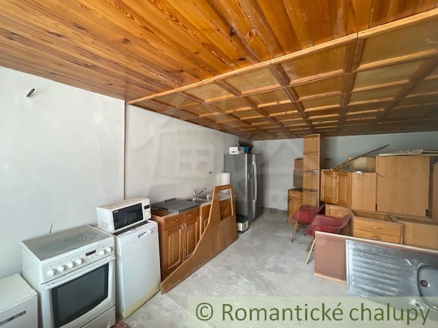 A kitchen in a family house with a wooden ceiling and a kitchen unit.