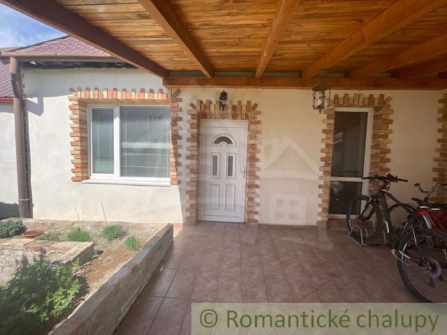 A family house in Palárikovo with a covered terrace, white doors, and bicycles.