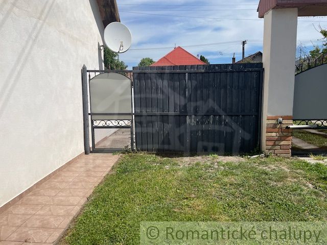 The courtyard of a family house in Palárikovo with a gate and a satellite dish.