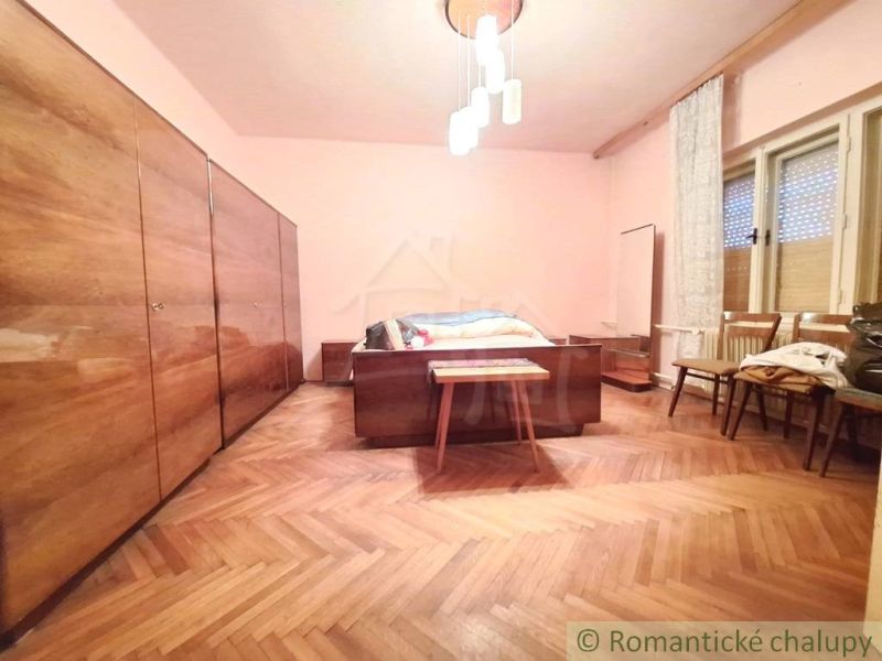 Bedroom in a family house with a wooden decor floor, chandelier, wardrobes, chairs.