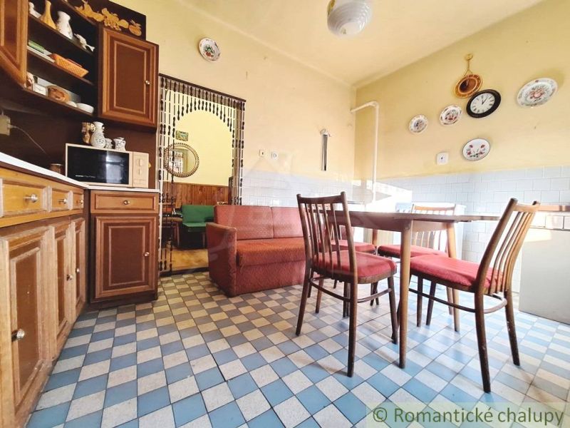 The kitchen of a family house with wooden furniture and tiled floor.