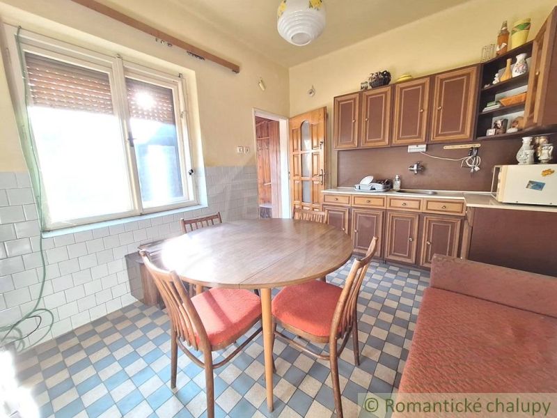 A kitchen in a family house with wooden cabinets and a tiled floor.