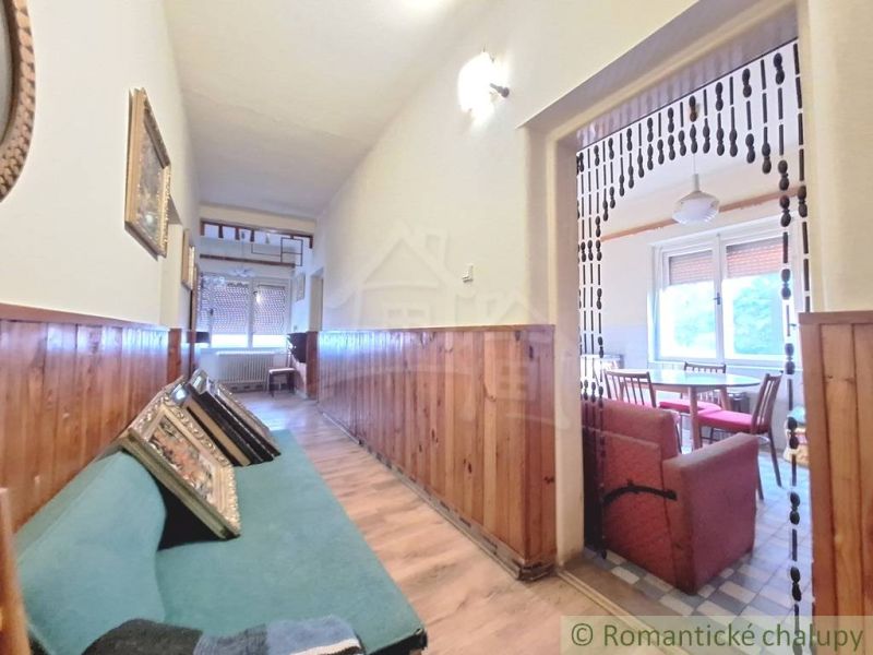 A hallway in a family house with wooden paneling and a view into the dining room.