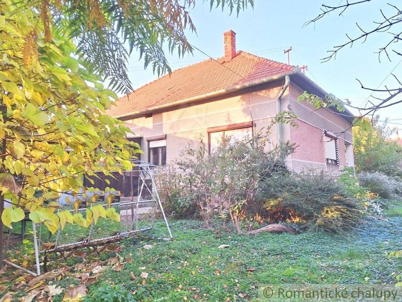 A family house in Gbelce with a garden swing, surrounded by greenery and shrubs.