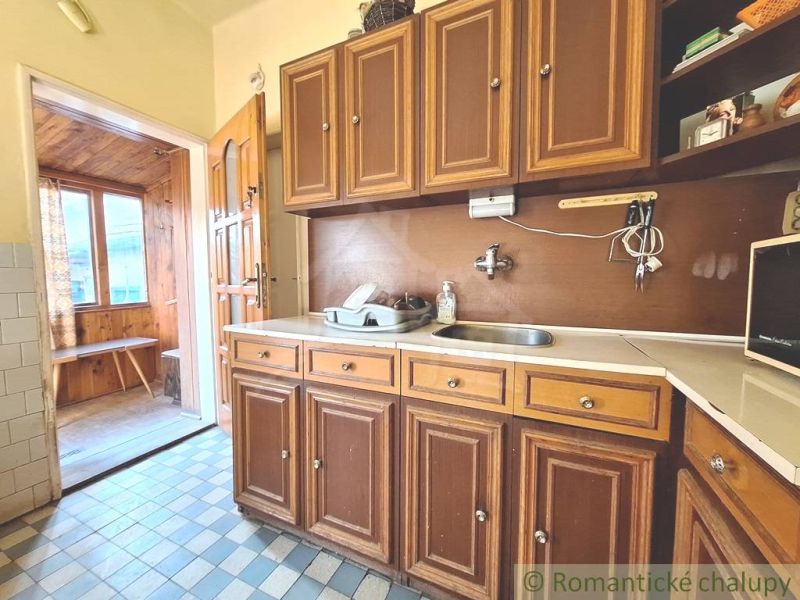 A kitchen in a family house with wooden cabinets and a tiled floor.
