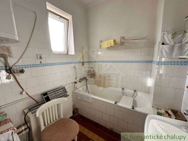 A bathroom in a family house with a bathtub, a window, and tiles.