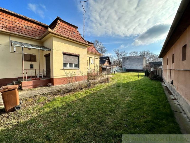 A family house in Kolárovo with a garden, lawn, and a shelter close to an adjacent building.