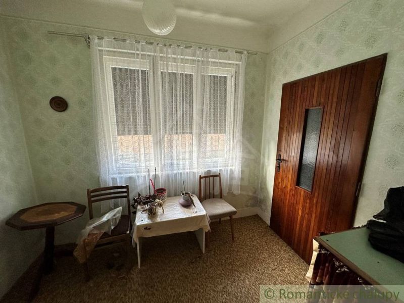 A room in a family house with lace curtains and a wooden table.