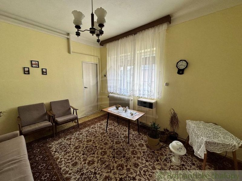 A living room in a family house with a carpet and curtains. Retro furniture complements the cozy atmosphere.