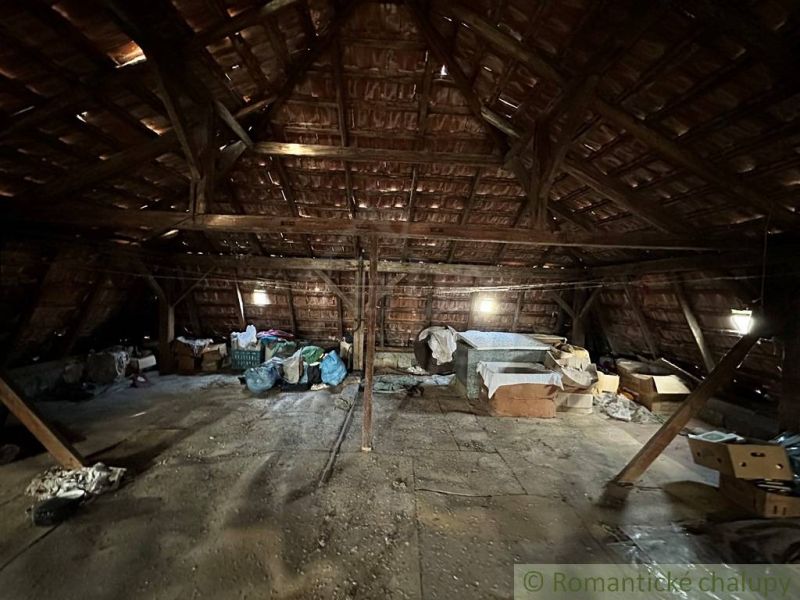 Attic in a family house with a sloped roof, stored items and diffuse light.