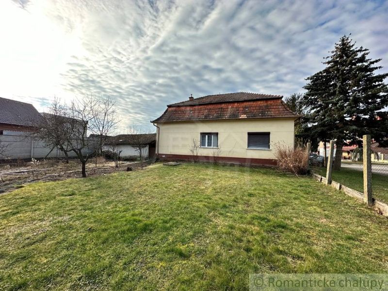 A family house in Kolárovo surrounded by a lawn, trees, and a fence.