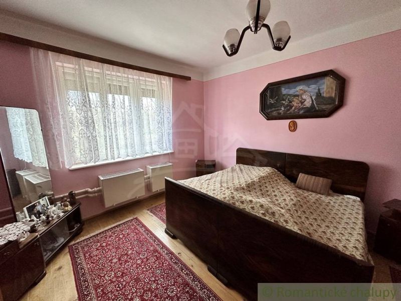 A bedroom with a double bed, wood-patterned flooring, and pink walls in a family house.
