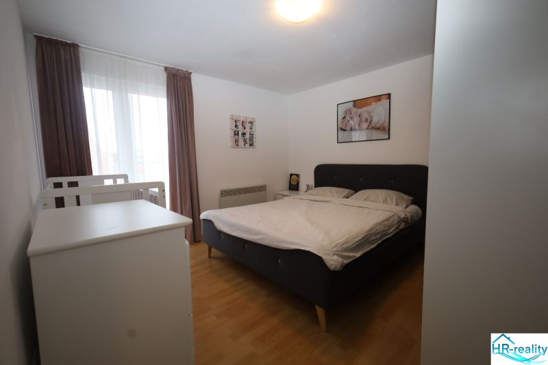 Bedroom with a bed and a baby crib in a holiday apartment, floor with wood decor.