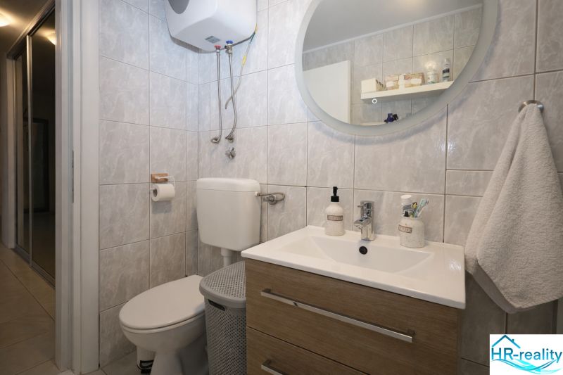 Bathroom in a Holiday Apartment with a sink, mirror, and toilet.