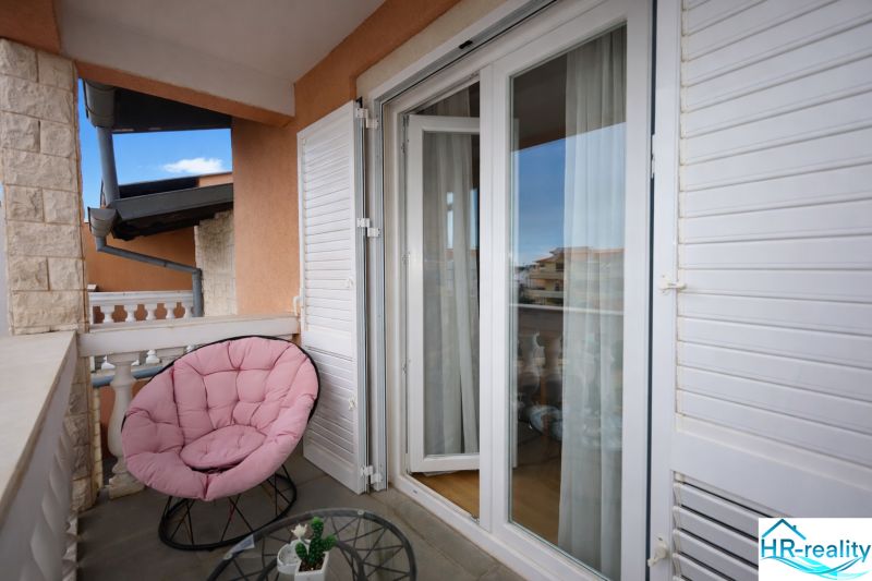 The balcony of a holiday apartment with a comfortable chair and a view of Vodice.