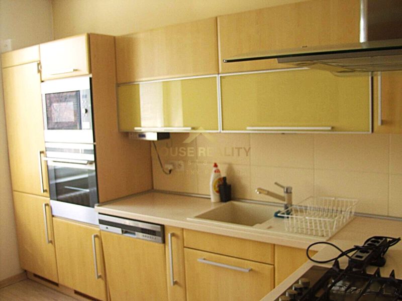 A kitchen in a 2-room apartment with built-in appliances and a wooden decor floor.
