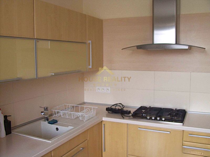 A kitchen in a 2-room apartment with a gas stove and an extractor hood, light cabinets.