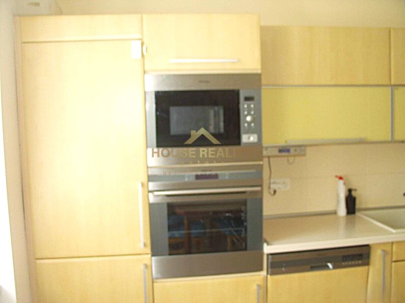 A kitchen in a 2-room apartment with built-in appliances and light furniture.