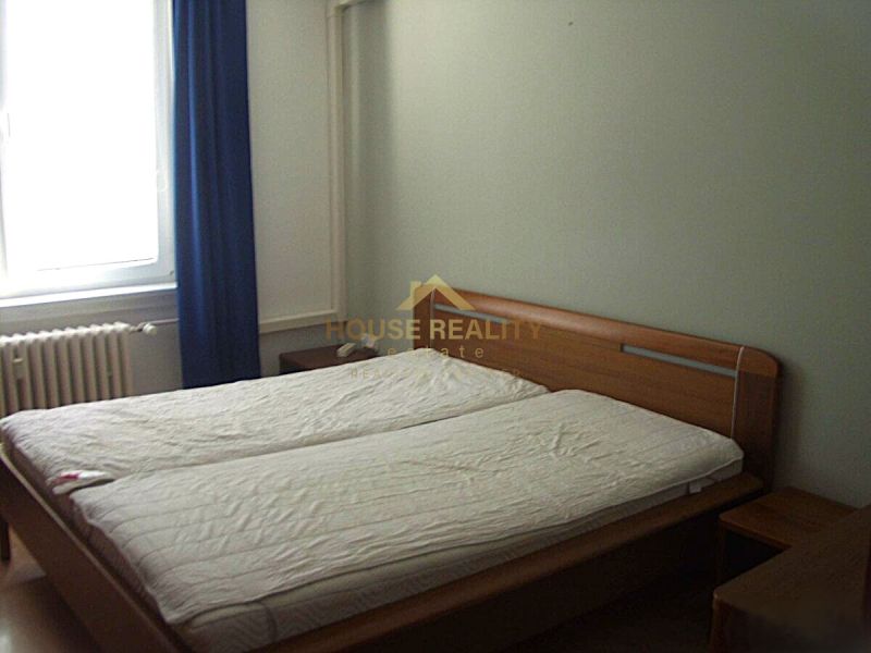 Bedroom in a 2-room apartment with a double bed, window, and curtain.