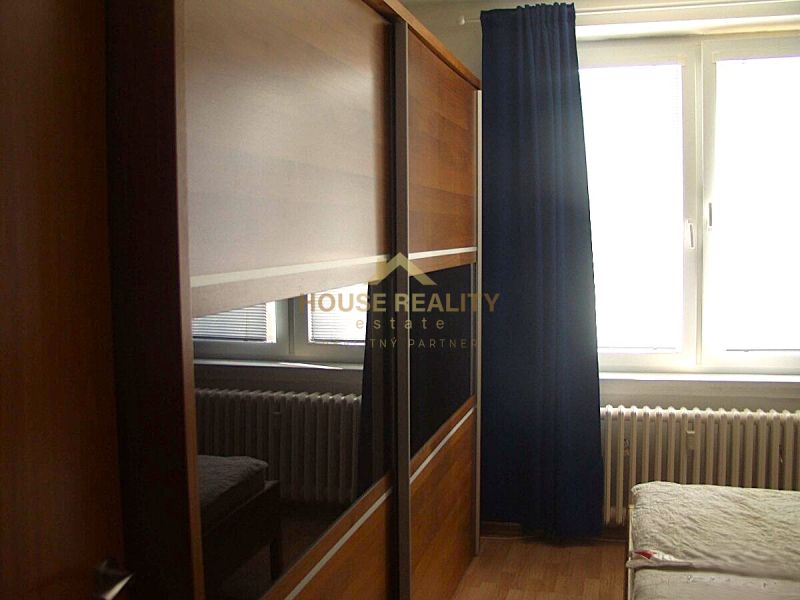 Sliding door wardrobe, bed, and radiator in the bedroom of a two-room apartment.