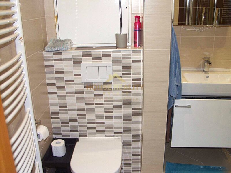 A bathroom in a 2-room apartment with a bathtub, sink, and tiles in neutral colors.