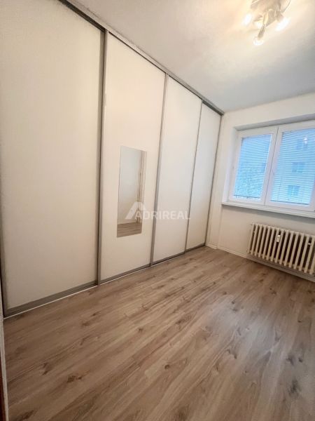 A room in a 3-room apartment with a white wardrobe and a wooden decor floor.