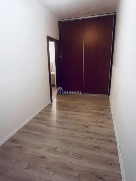 A hallway with a built-in wardrobe and a floor with a wood decor in a 3-room apartment.