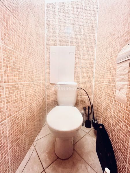 A toilet with mosaic tiles in a 3-room apartment, bright and clean environment.