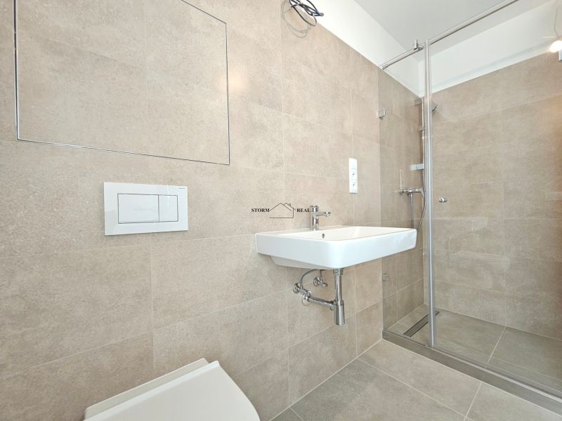 Bathroom in a studio apartment with a toilet, shower, and sink in a minimalist style.