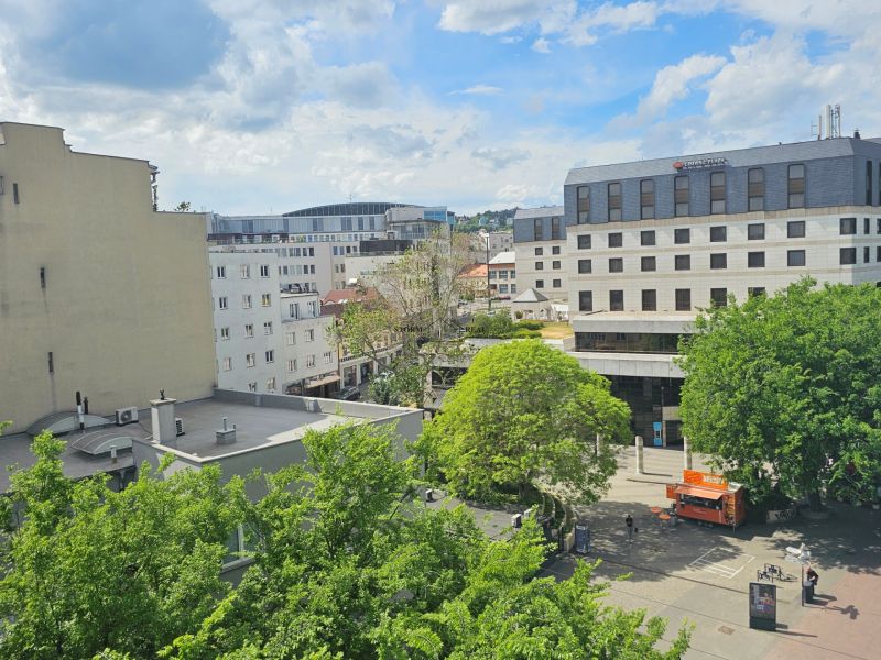 View of Poštová Street in Bratislava - Old Town with greenery and buildings.