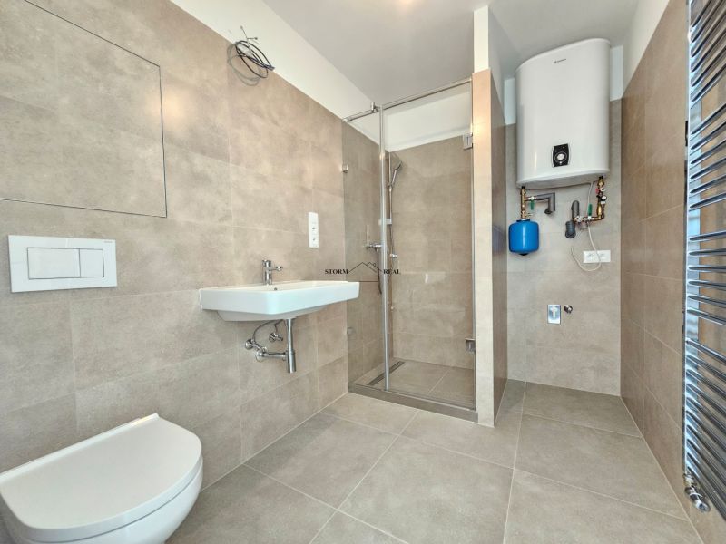 A bathroom in a studio apartment with a shower and a gas boiler.