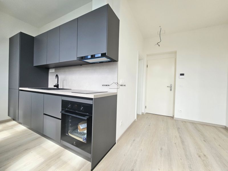 A kitchen unit with a built-in oven and a floor with a wooden decor in a studio apartment.