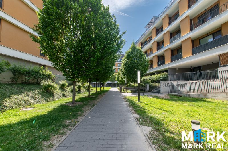 Bajkalská Street in Bratislava with apartment buildings and trees along the sidewalk.