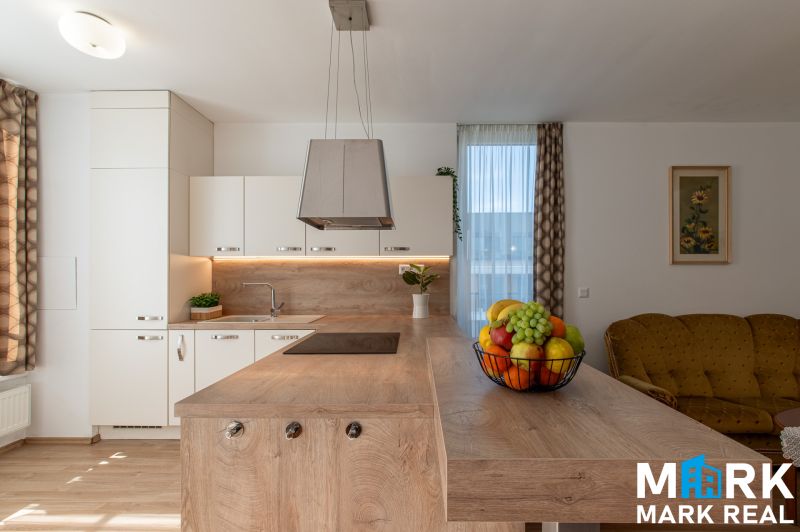 A kitchen with an island and fruit in a 2-room apartment, floor with a wooden decor.