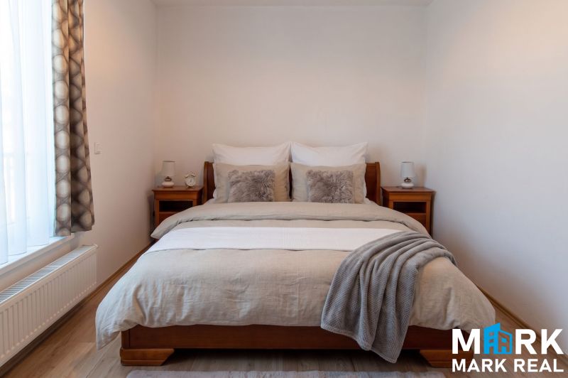 Bedroom with a bed and wooden furniture in a 2-room apartment, floor with wooden decor.