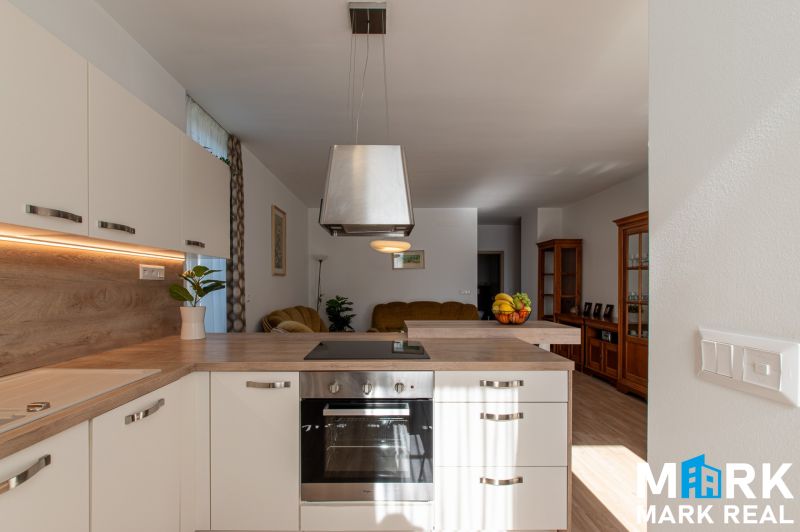 A kitchen in a 2-room apartment with a wooden decor floor and white cabinets.