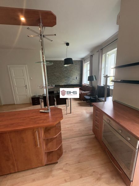 The kitchen of a 2-room apartment with a wooden decor floor and a modern counter.