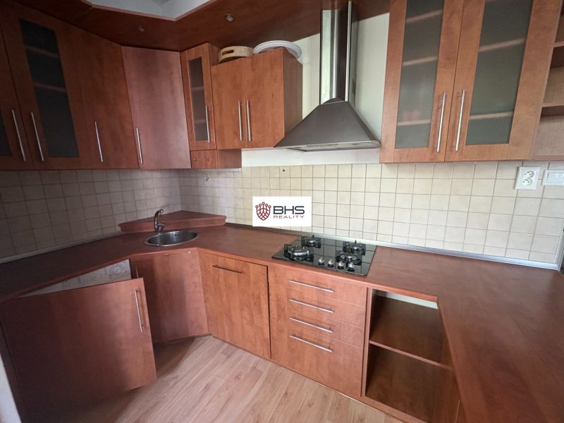 A kitchen in a 2-room apartment with a wooden decor floor and a brown kitchen unit.