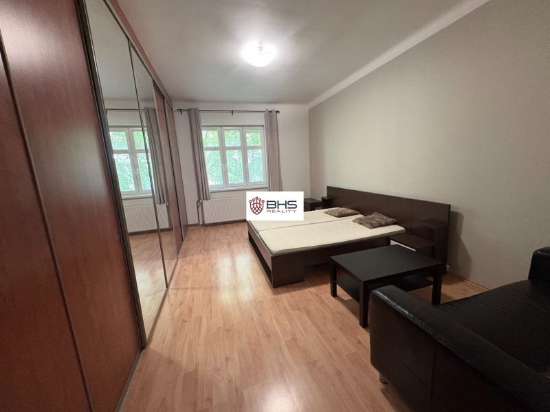 A spacious bedroom in a 2-room apartment with a wood-patterned floor and built-in wardrobes.