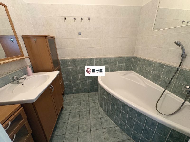 Bathroom with a bathtub, sink, and cabinet in a 2-room apartment, tiles and wall tiles.