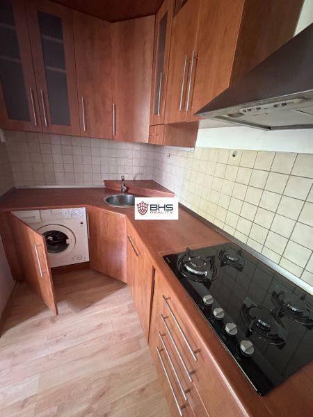 A kitchen in a 2-room apartment with a wooden decor floor and built-in appliances.
