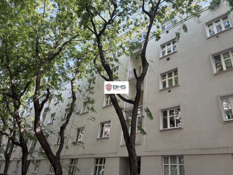 White apartment building on Dobrovského Street in Bratislava's Old Town, surrounded by greenery.